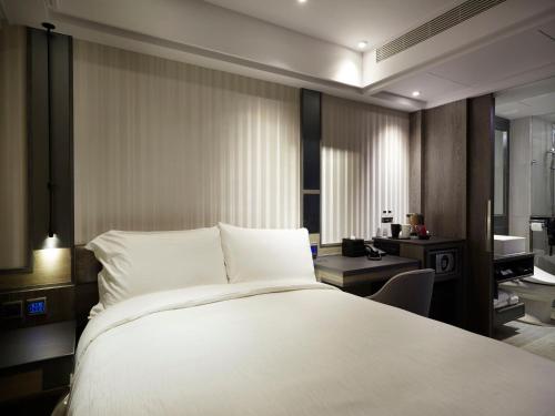 a bedroom with a large white bed and a desk at At Home Hotel Ximen in Taipei