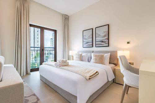 a white bedroom with a large bed and a desk at Charming Studio next 5 min walk to Formula 1, Golf Course, and Yas Water World in Abu Dhabi