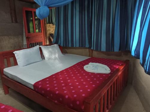 a small bed with a red and white blanket on it at River cottage Demodara in Demodera