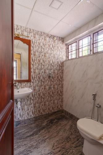 a bathroom with a toilet and a sink and a mirror at Orma in Cochin