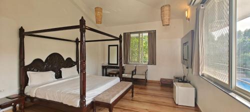 a bedroom with a bed and a desk and a window at The HighGarden Resort in Udaipur
