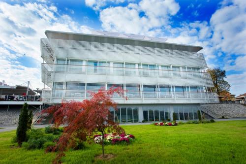 a white building with a tree in front of it at Hotel Navis in Orašje