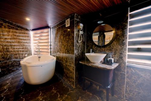 a bathroom with a tub and a sink and a mirror at Amanda cruise 5 star ha long bay in Ha Long