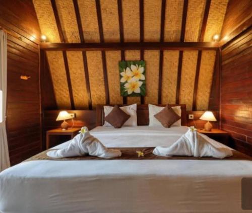 a bedroom with a bed with two pillows on it at Bataran Garden Cottage in Nusa Penida