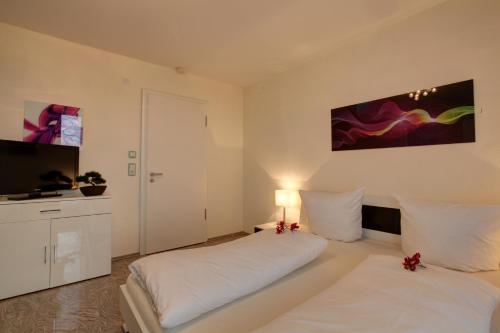 a bedroom with two beds and a flat screen tv at Hotel Jungstil in Darmstadt