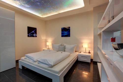 a bedroom with a large white bed with two lamps at Hotel Jungstil in Darmstadt