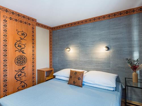 a bedroom with a blue bed with a wooden wall at WERONIKA Murzasichle - podgrzewany basen zewnętrzny śniadanie i jacuzzi w cenie in Murzasichle