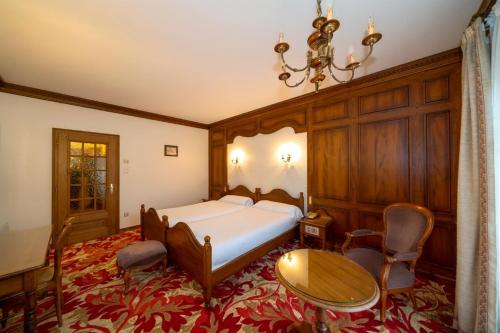 a bedroom with a bed and a table and chairs at Hotel Munsch Restaurant & Wellness, Colmar Nord - Haut-Koenigsbourg in Saint-Hippolyte