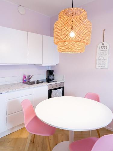 a white kitchen with a white table and pink chairs at Studio Flamingo in Helsinki