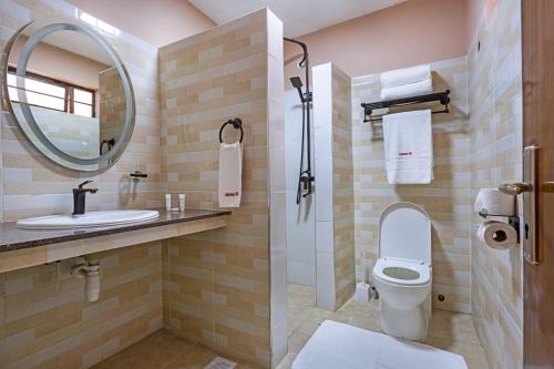 a bathroom with a toilet and a sink and a mirror at Lukenya Motorcross in Machakos