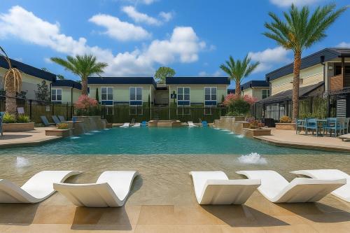 a large swimming pool with white chairs and palm trees at Stunning 1BR near The Heights with BBQ, Gym & Pool in Houston