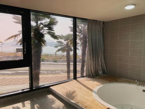 a bathroom with a tub and a view of the ocean at Arte Resort Spa & Pool Villa in Sacheon