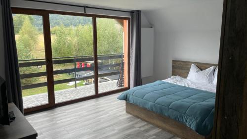 a bedroom with a bed and a large window at Pensiunea Panoramic in Stațiunea Climaterică Sâmbăta
