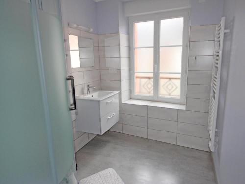 une salle de bains blanche avec un lavabo et une fenêtre dans l'établissement La treille, à Saint-Hilaire-La-Treille