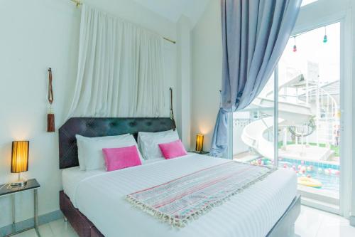 a bedroom with a bed with pink pillows and a window at สายป่าน พลูวิลล่า in Cha Am