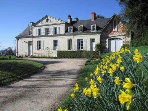 a large white house with yellow flowers in front of it at Chambres d'Hôtes Le Château de la Plante in Thuré