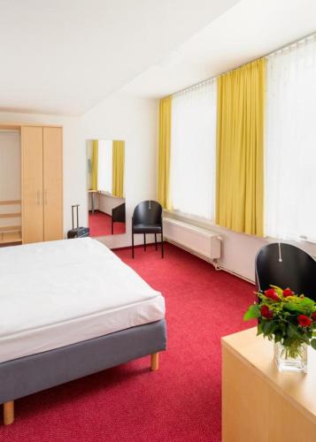 a hotel room with a bed and two chairs at CVJM Düsseldorf Hotel & Tagung in Düsseldorf