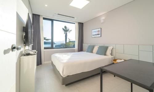 a bedroom with a bed and a desk and a window at Arte Resort Spa & Pool Villa in Sacheon