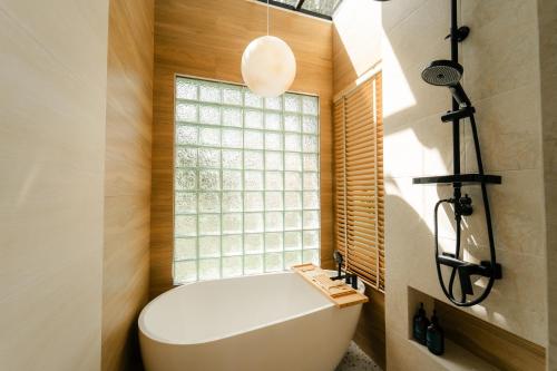 a bathroom with a white tub and a window at PHUM Villa Songkhla in Ban Saphan Yao