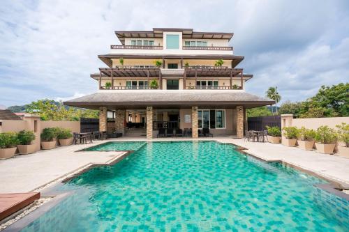 a hotel with a swimming pool in front of a building at Ratana Hotel Chalong in Rawai Beach