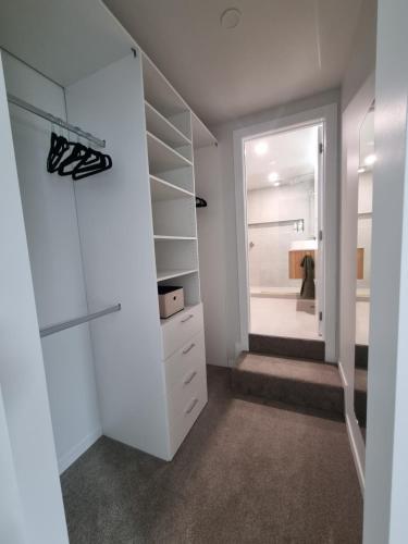 a walk in closet with white cabinets and a mirror at Luxury Town house with fabulous views in Hamilton