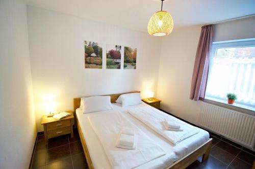 a bedroom with a bed with white sheets and a window at Störtebeker in Norddeich
