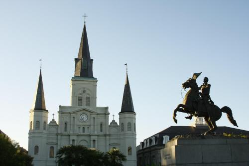 a statue in front of a building with a cathedral at NOLA Condos in New Orleans