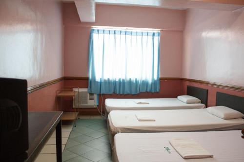 a room with three beds and a window at GV Hotel - Maasin in Maasin