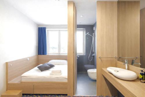 a bedroom with a bed and a bathroom with a sink at Kongres Hotel Roca in Košice
