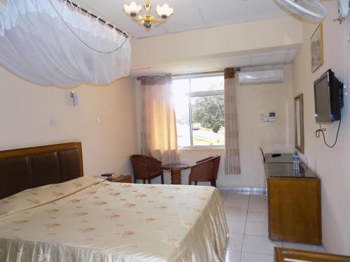 a bedroom with a bed and a table and a window at Hotel Oasis in Morogoro