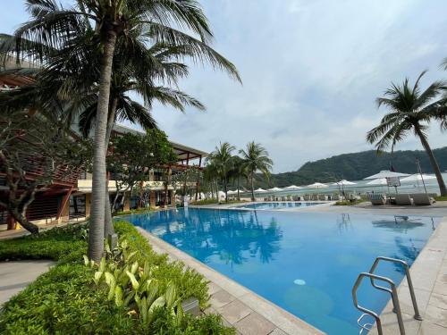 a large swimming pool with palm trees and buildings at Beach condos at Pico de Loro Cove & possible Beach Club Access & Wi-Fi & Netflix, 42-50''TVs with Uratex beds & pillows, equipped kitchen, balcony, parking, guest registration fee is not included in Nasugbu