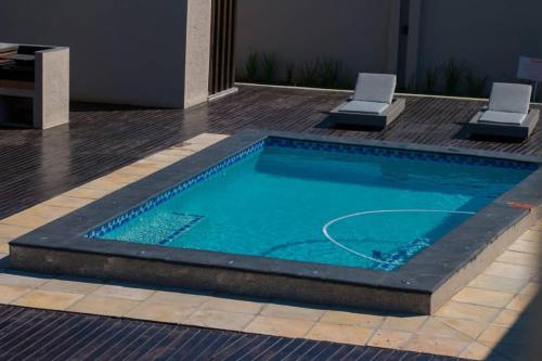 Simphiwe Guesthouse في منزيني: مسبح كبير به كرسيان في مبنى