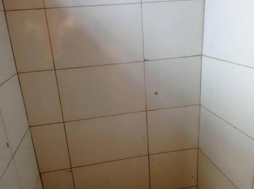a tiled shower with white tiles on the wall at Jayson Housing in Wakiso
