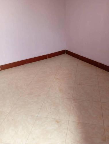 an empty room with a tile floor and white walls at Jayson Housing in Wakiso