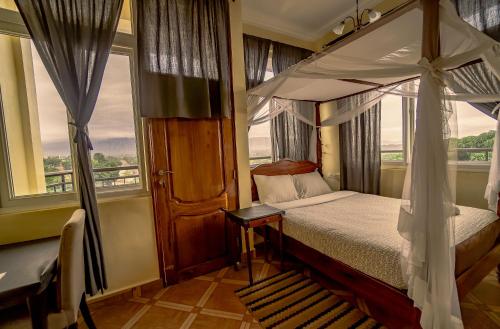 a bedroom with a canopy bed and a window at East Point Hotel Moshi in Moshi