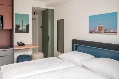 a bedroom with a white bed with a blue headboard at Homaris Nolli Studios in Berlin