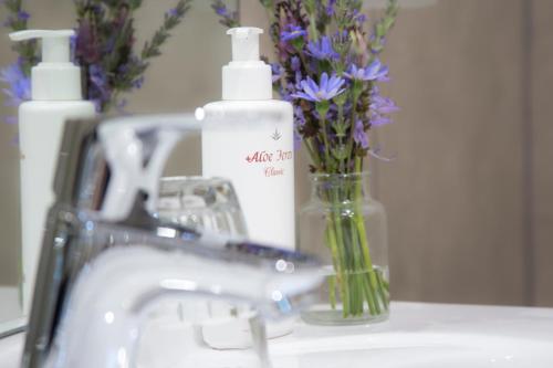 a sink with a vase of flowers next to a mirror at Maroela House Guest Accommodation in Bellville