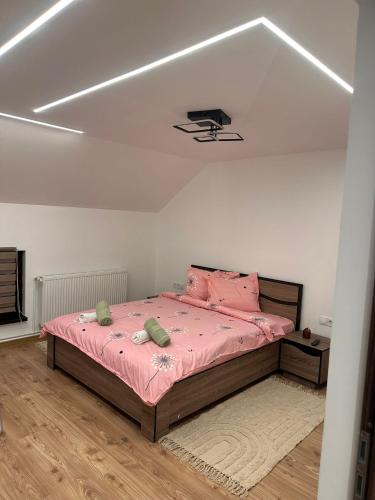 a bedroom with a large bed with pink sheets at The Forest Nest Apartment in Sărmaş