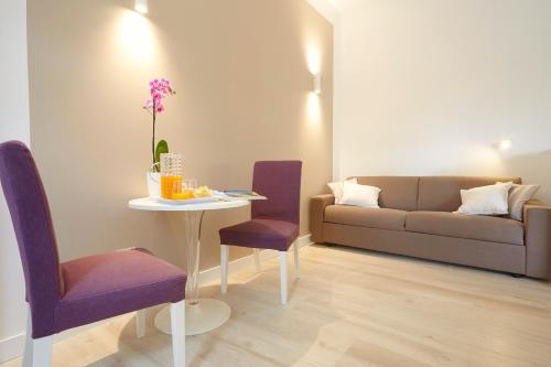 a living room with a couch and a table and purple chairs at B&B Mondello Design in Mondello