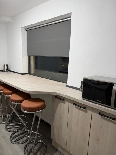a kitchen with a counter with a microwave and stools at Central Villa in Craiova