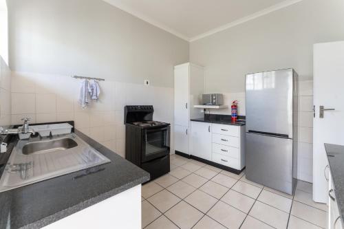 a kitchen with a sink and a refrigerator at Fairway Holiday Accommodation in Hermanus