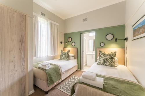 two beds in a room with green walls at Fairway Holiday Accommodation in Hermanus