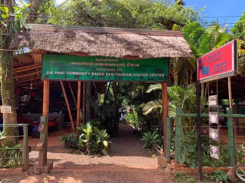 កុយ ឡាយ-Koy Lay في Chi Phat: لافتة أمام مبنى بسقف من القش