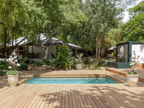 a garden with a swimming pool and trees at The Tin Roof in Riebeek-Kasteel