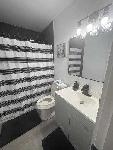 a bathroom with a black and white shower curtain and a toilet at Family Home WITH 3 BR & 1RR in Grand Prairie