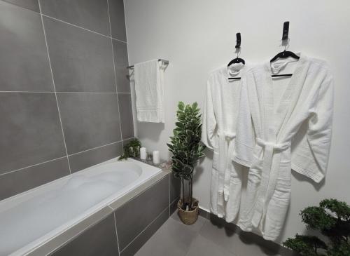 a white bathroom with a bath tub and a white robe at Luxury Spa unit, Private Sauna, Central Ballito in Ballito