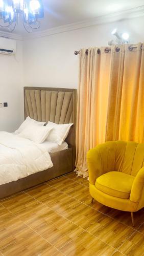 a bedroom with a bed and a yellow chair at Perfect Home in Lagos