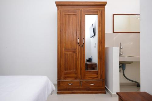 a wooden cabinet in a bedroom next to a bed at Urbanview Hotel Arta Guna Casa in Kerobokan