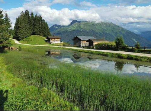 a lake in front of a house and a mountain at Ferienhaus Fritzensee in Bartholomäberg