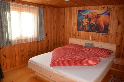 a bedroom with a bed with a cow painting on the wall at Ferienhaus Fritzensee in Bartholomäberg